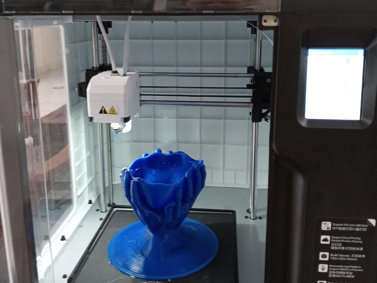 A desktop 3D printer printing a blue vase